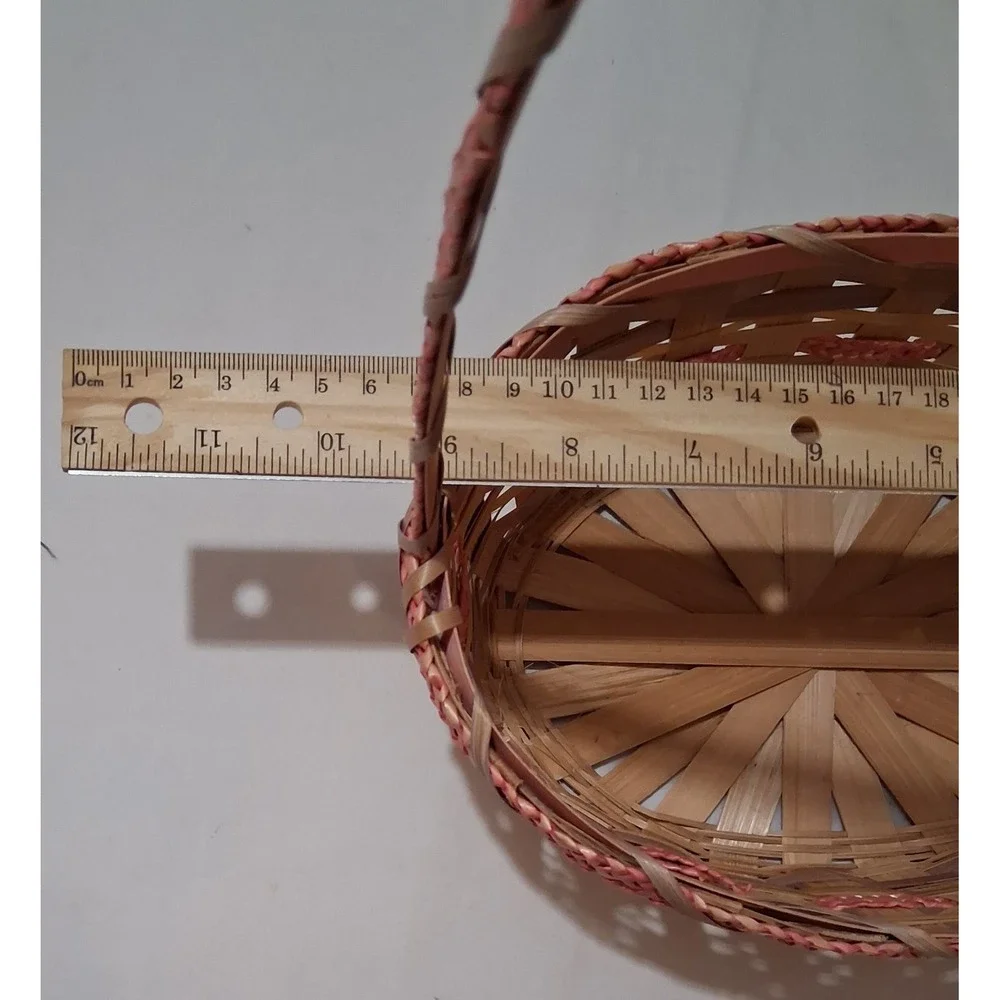 Two vintage woven bamboo baskets with‎ tall handles and pink accenting.